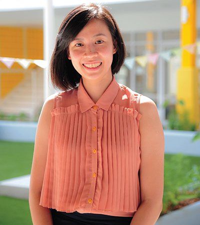 A woman in a pink pleated shirt is smiling for the camera