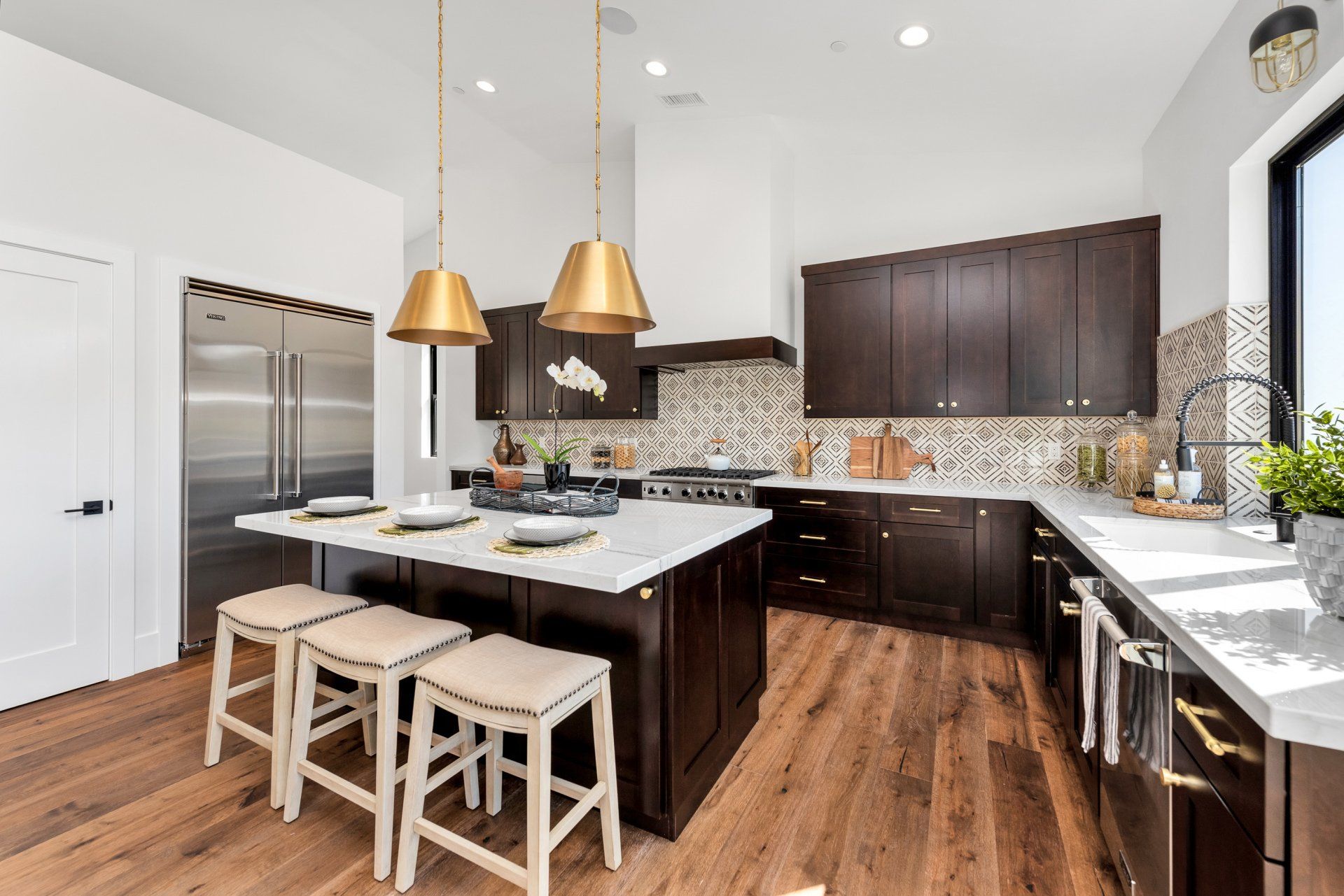 A kitchen with stools and a large island in the middle.