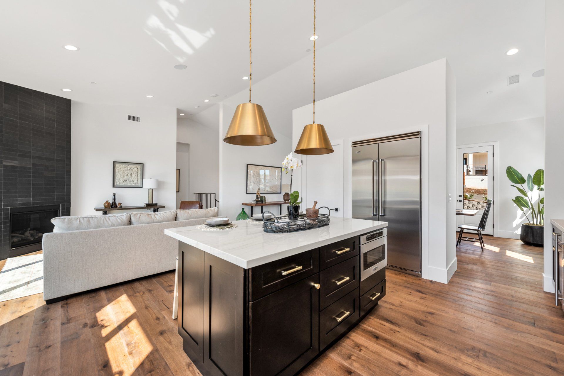 A kitchen island with dark cabinets, a built in oven, and white countertops with decorations on them.