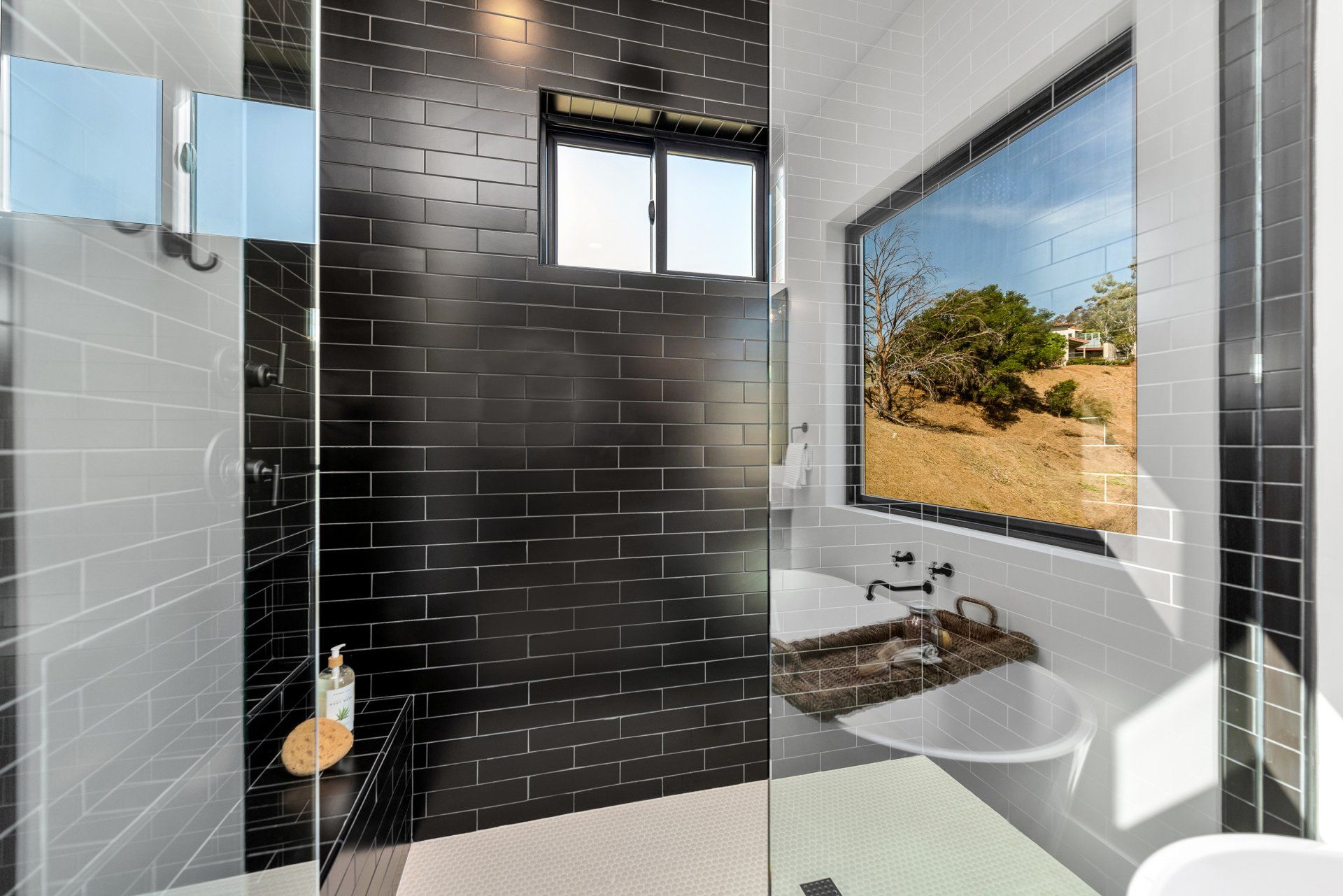 A bathroom with black tiles and a walk in shower.