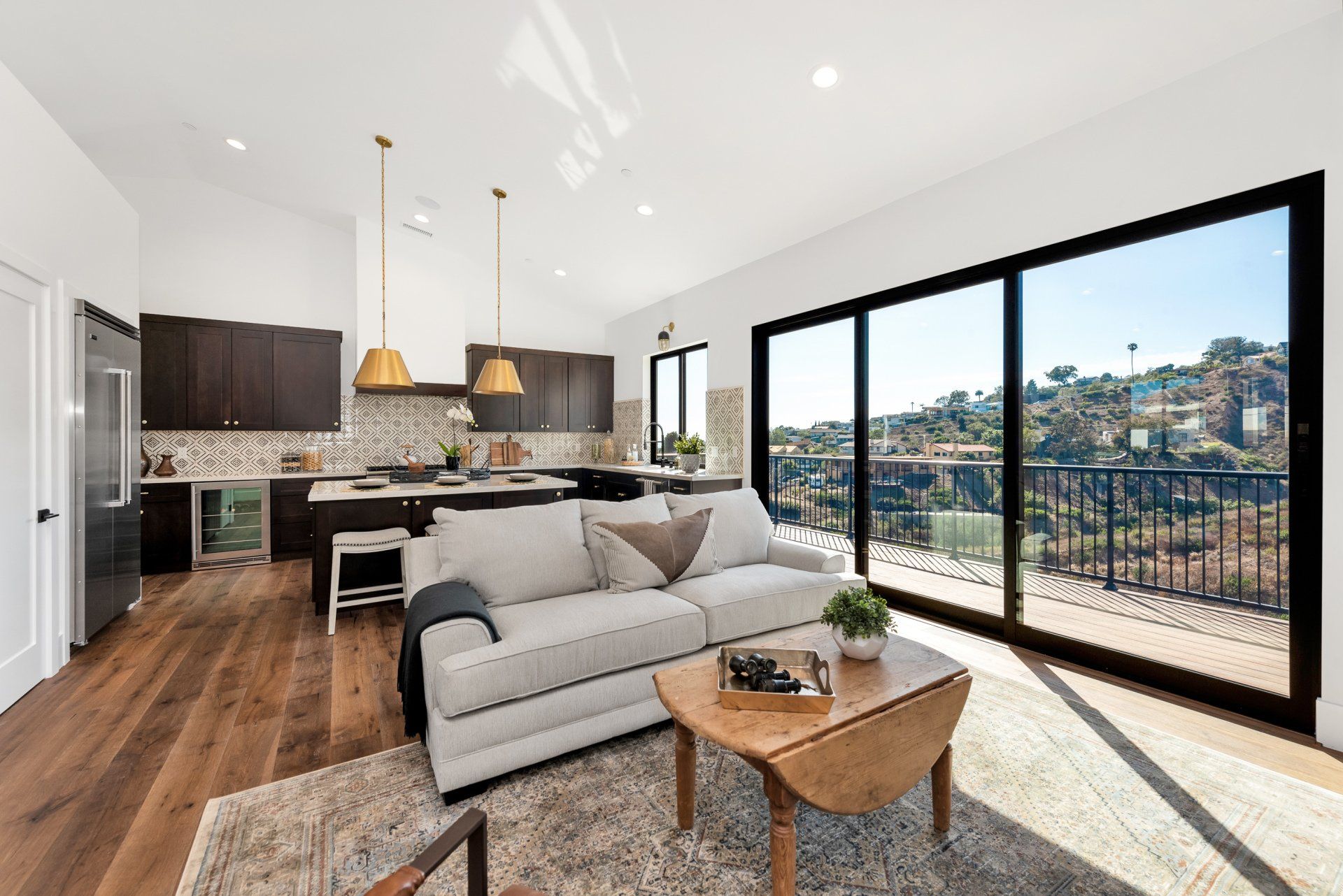 A living room with a couch, coffee table, sliding glass doors, and the kitchen in the background.