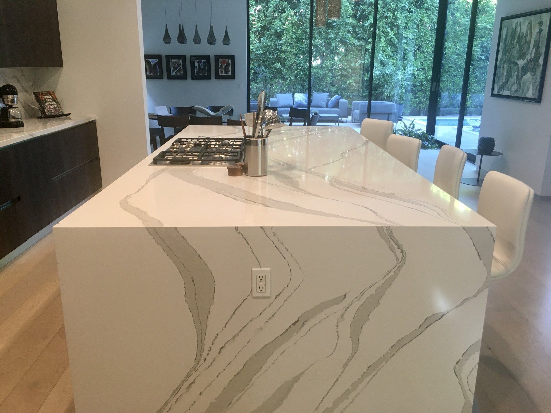 A kitchen with a large marble island and a stove top oven.