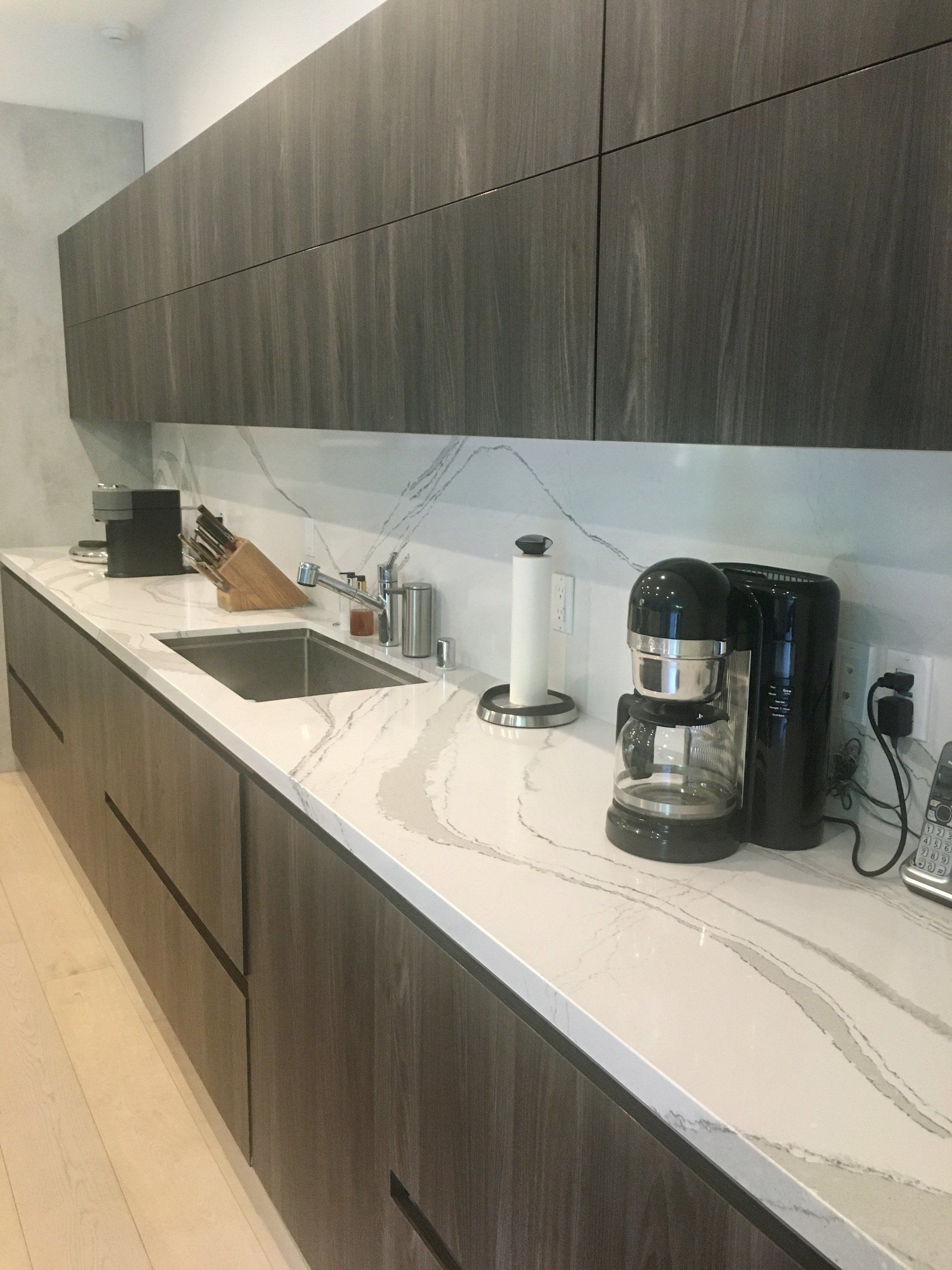 Marble kitchen counters with a sink and a coffee maker on the counter.