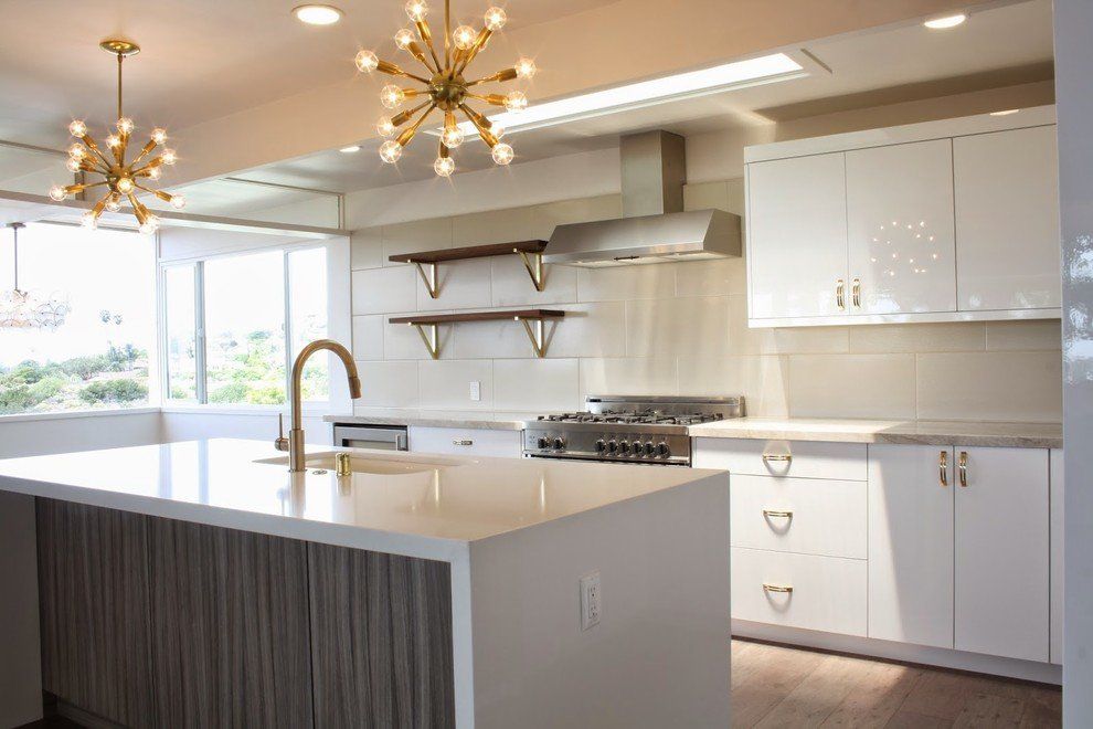 A kitchen with white cabinets, a stove, a sink, and a large white island.