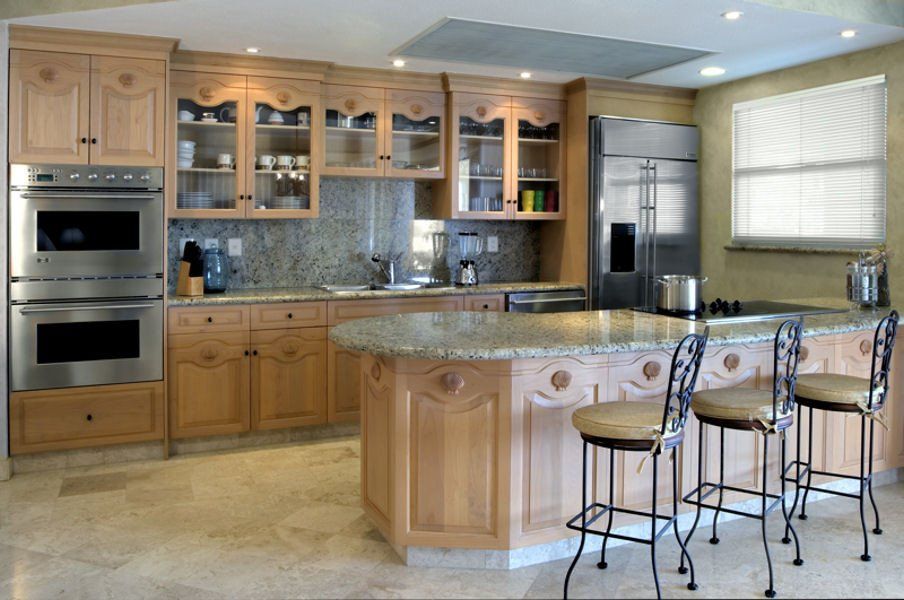 A kitchen with stainless steel appliances, wooden cabinets, a rounded island, and a stone backsplash.