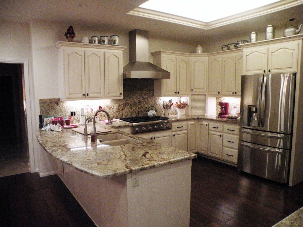 A kitchen with white cabinets, stainless steel appliances, and natural stone countertops.
