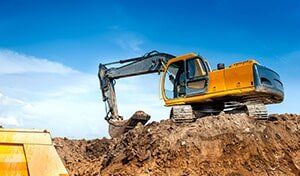 An excavator is digging a pile of dirt in a construction site.