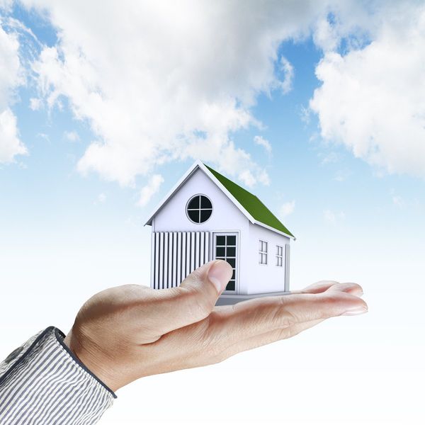 Hand holding a house in palm.