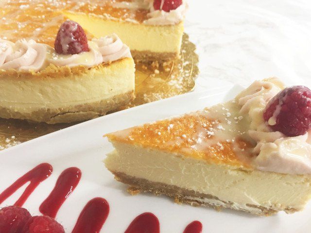 A slice of cheesecake with raspberries on top on a white plate