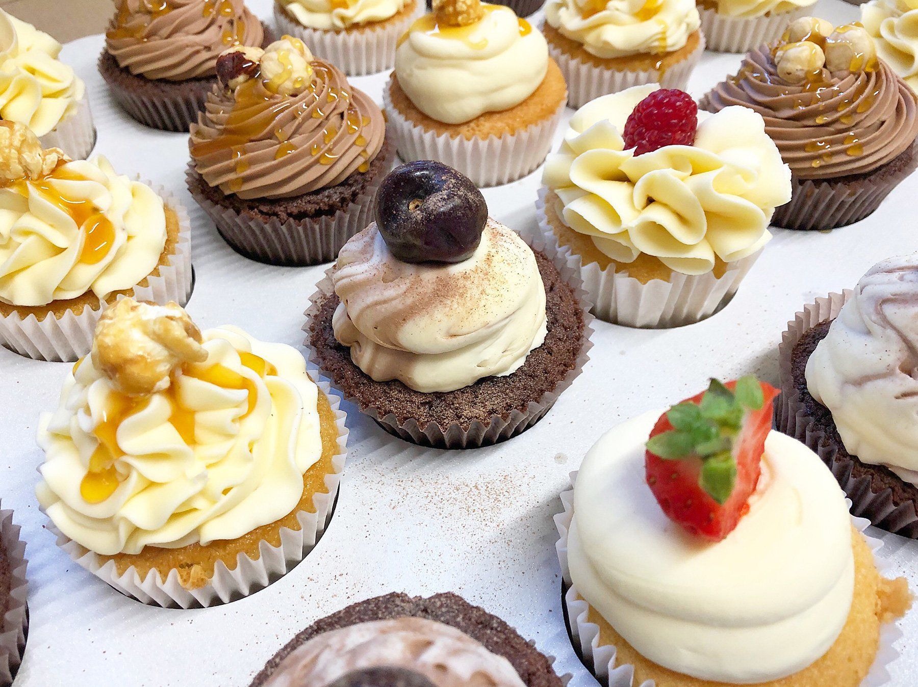 A box of cupcakes with different flavors and frosting