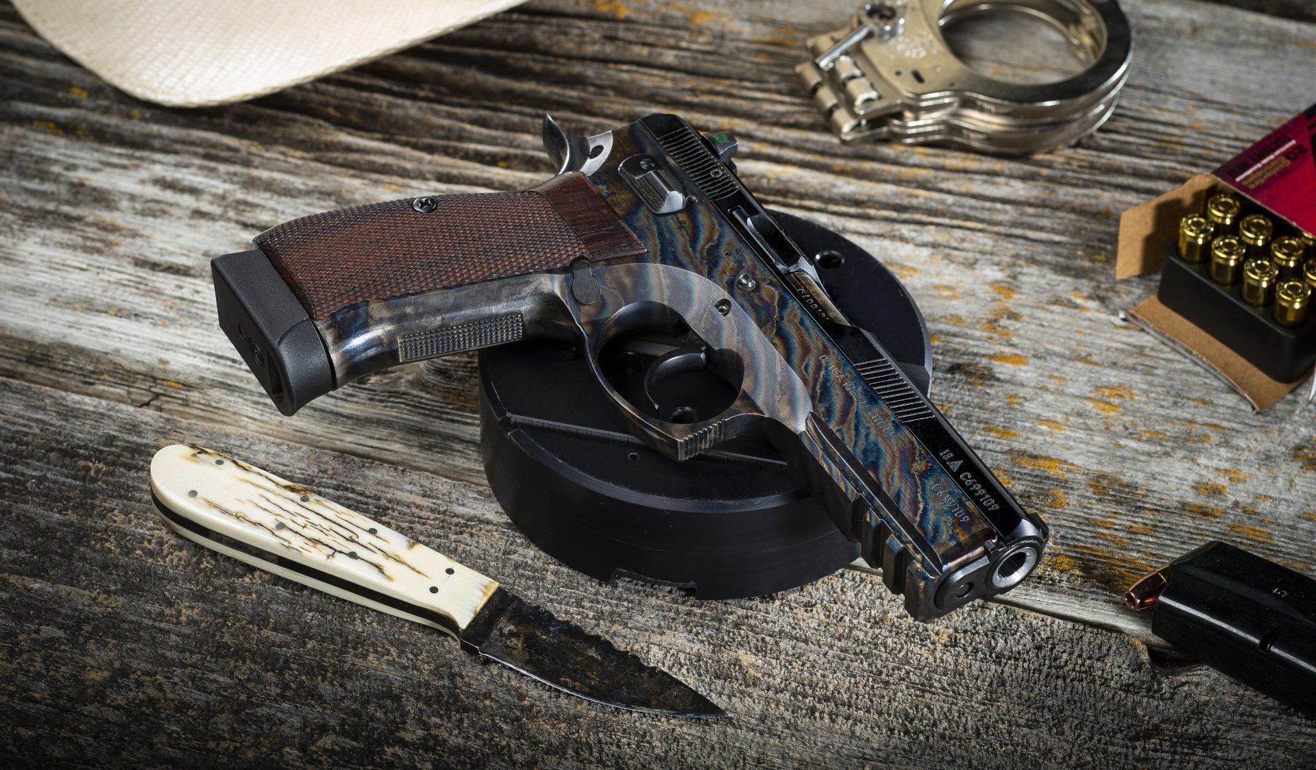 Pistol, handcuffs, knife, and ammunition on a wooden surface, suggesting crime scene setup.