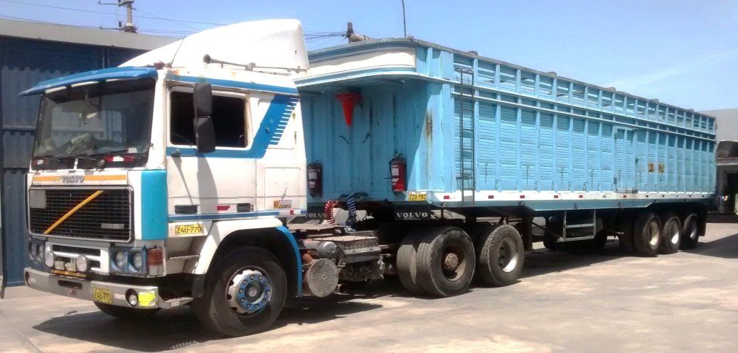 Un camión semirremolque azul y blanco con un remolque azul a juego estacionado afuera.