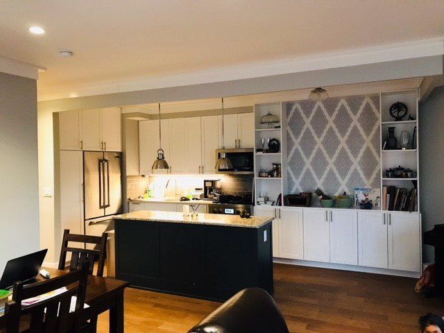A kitchen with white cabinets and a black island