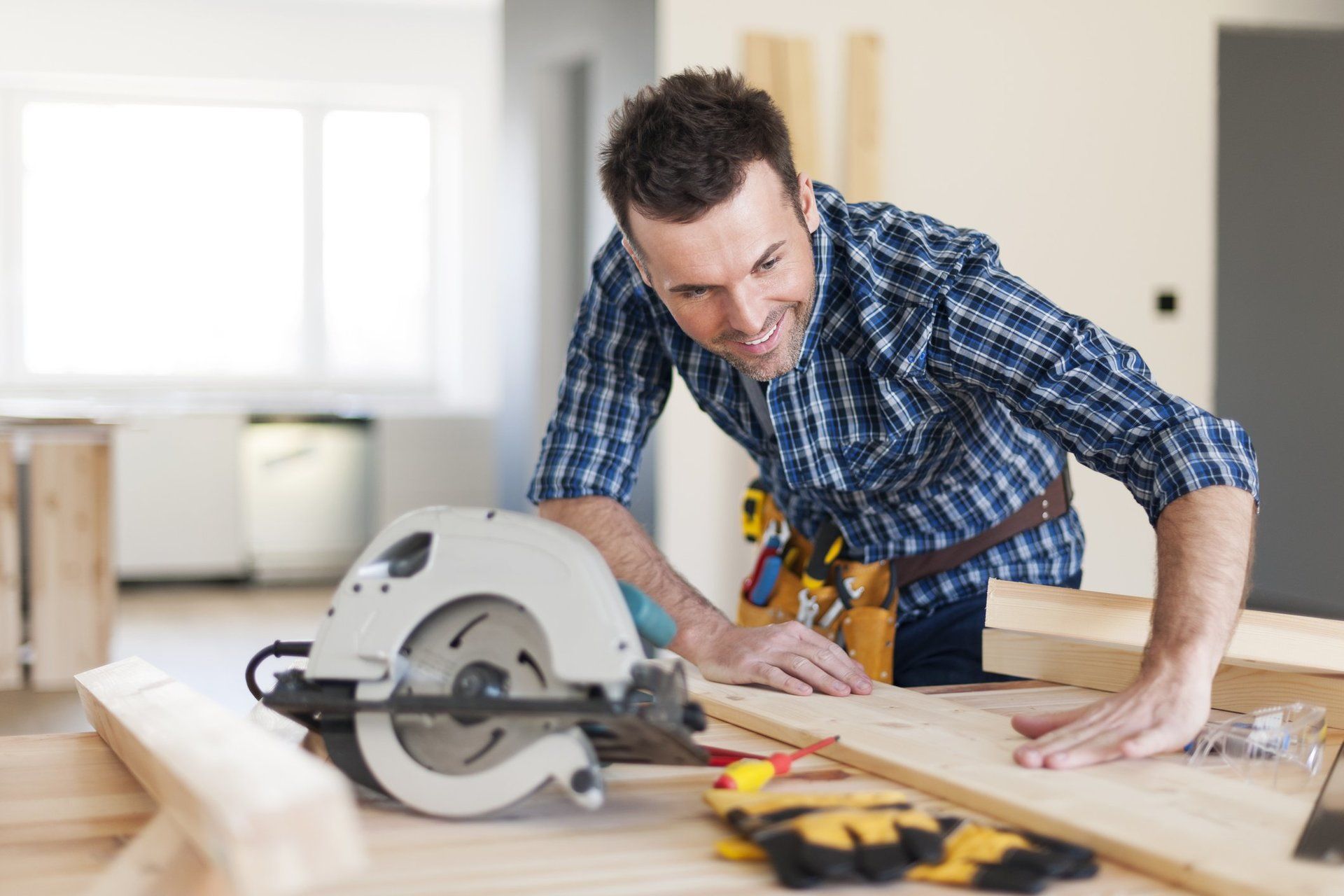 A man is using a circular saw to cut a piece of wood.