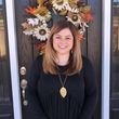 A woman is standing in front of a door with a wreath on it.