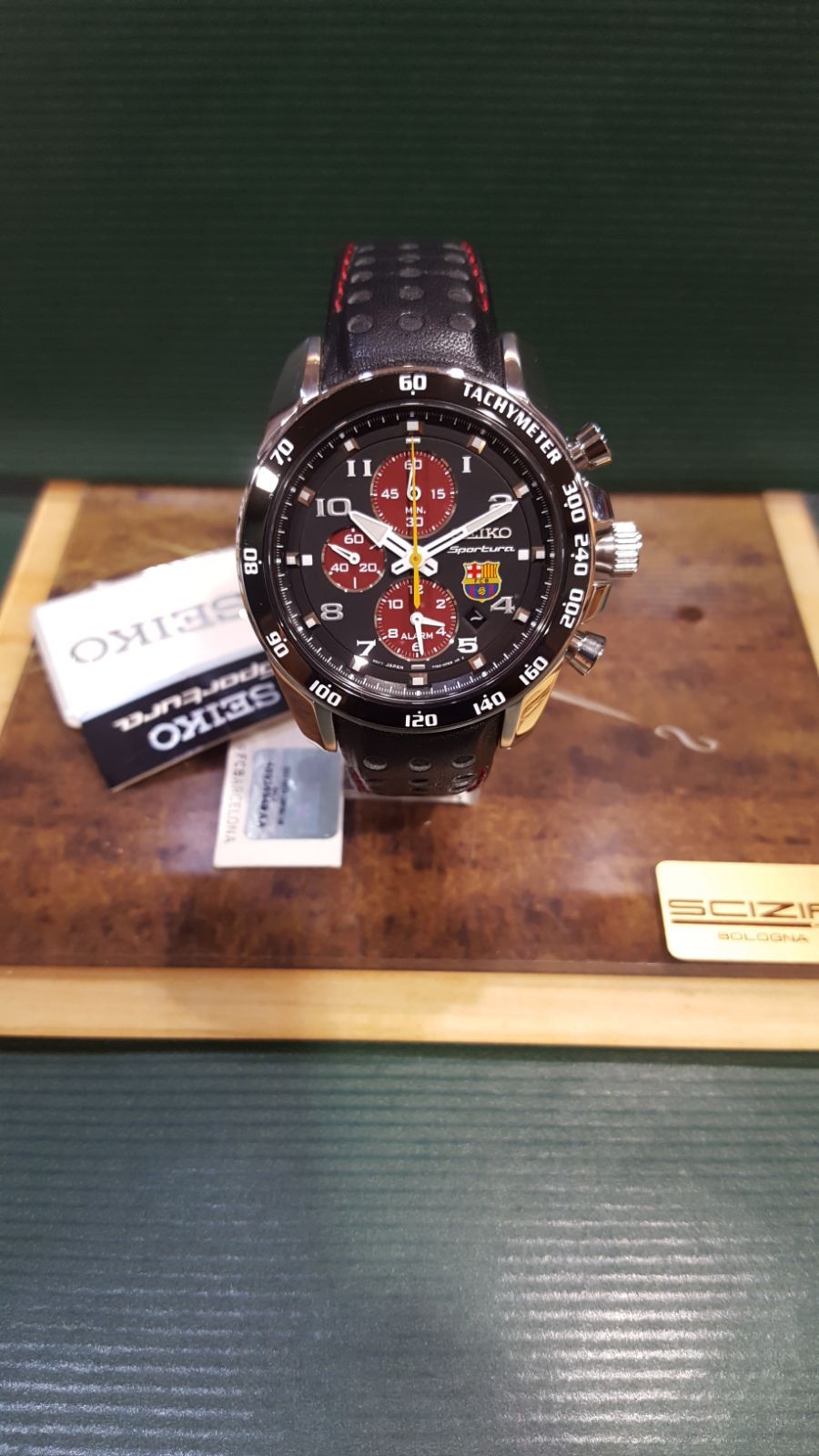 Orologio cronografo Seiko con quadrante nero, dettagli rossi e cinturino in pelle, esposto su una superficie di legno.