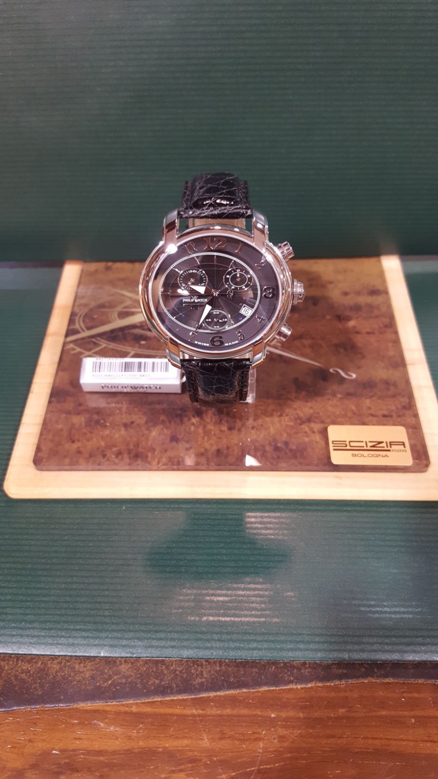 Orologio in argento con cinturino in pelle nera su espositore in legno.
