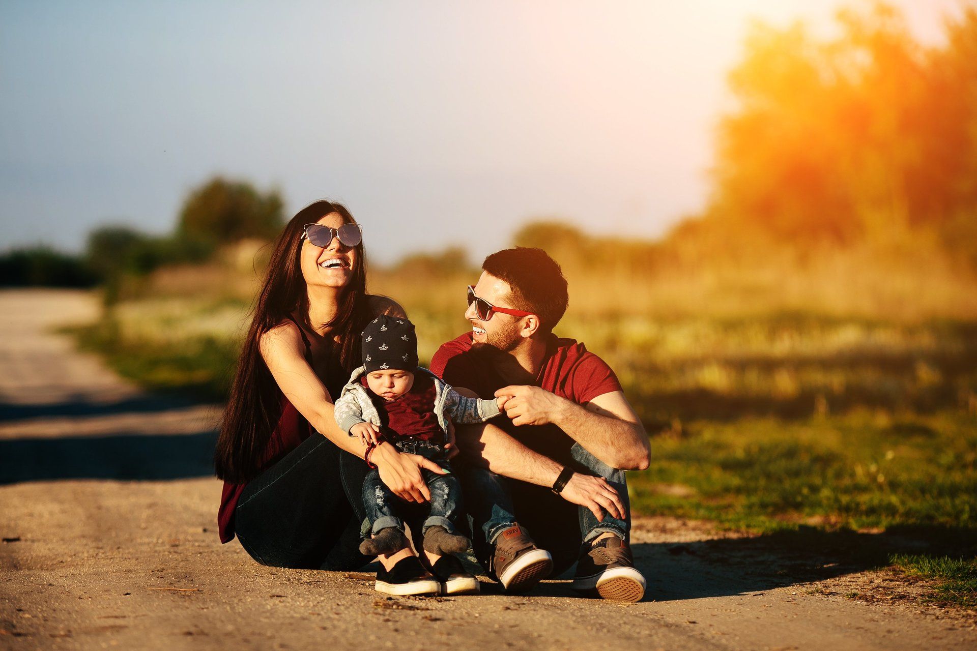 stock photo of a couple sitting outdoors in sunny weather with their baby