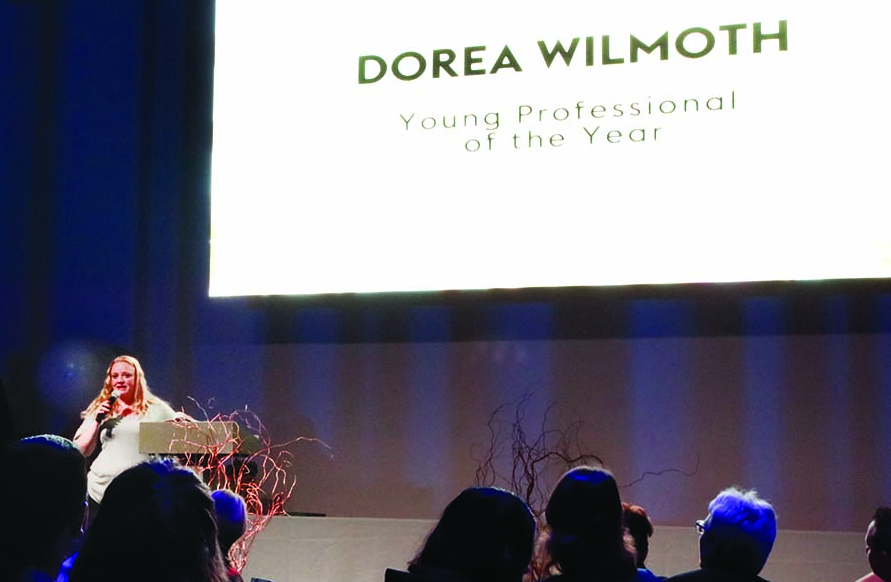 Dorea Wilmoth accepting Young Professional of the Year award, speaking from stage during the banquet
