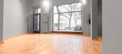 An empty room with hardwood floors and a large window.