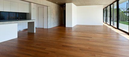 A large empty room with a wooden floor and lots of windows.