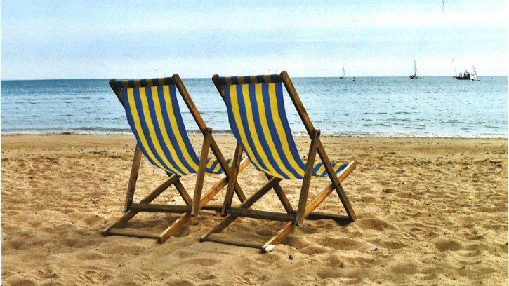 Two striped beach chairs on sandy shore facing calm ocean