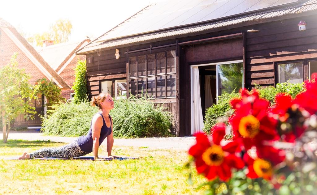 Willemijn in een yoga-pose in de zon op het buitenveld.