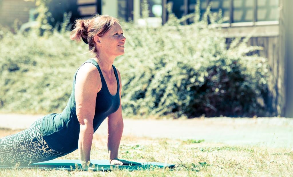 Willemijn in een yoga-pose op het veldje waar bij mooi weer buiten les wordt gegeven.