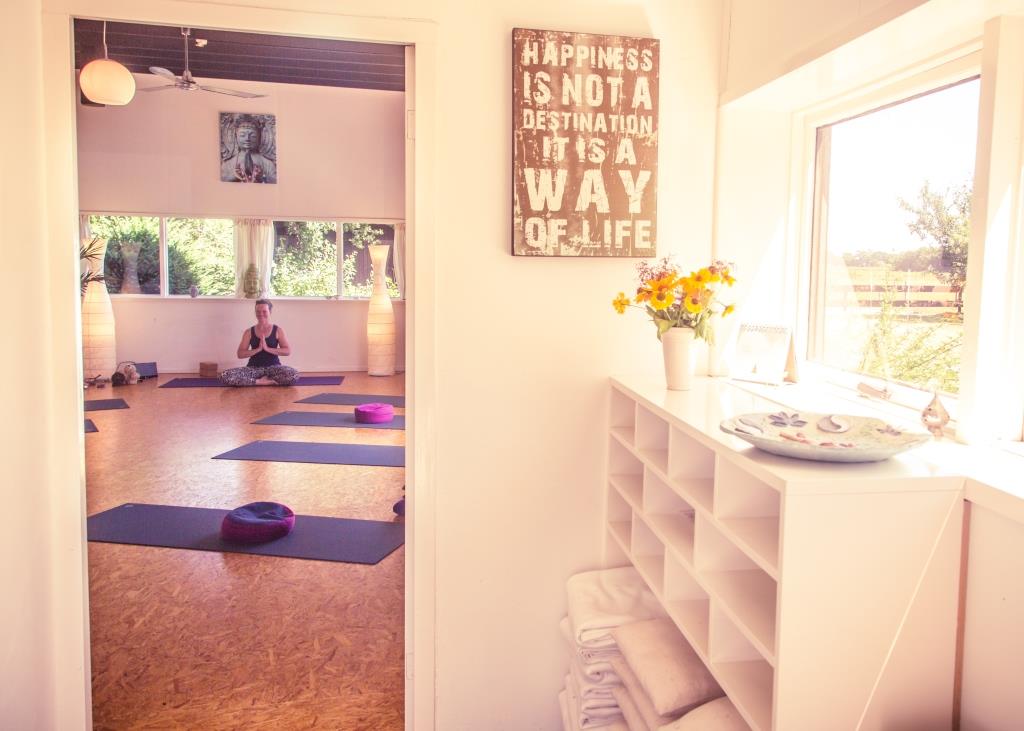 Het halletje van Yoga Atelier Epe met een blik naar binnen waar Willemijn in een yoga pose zit.