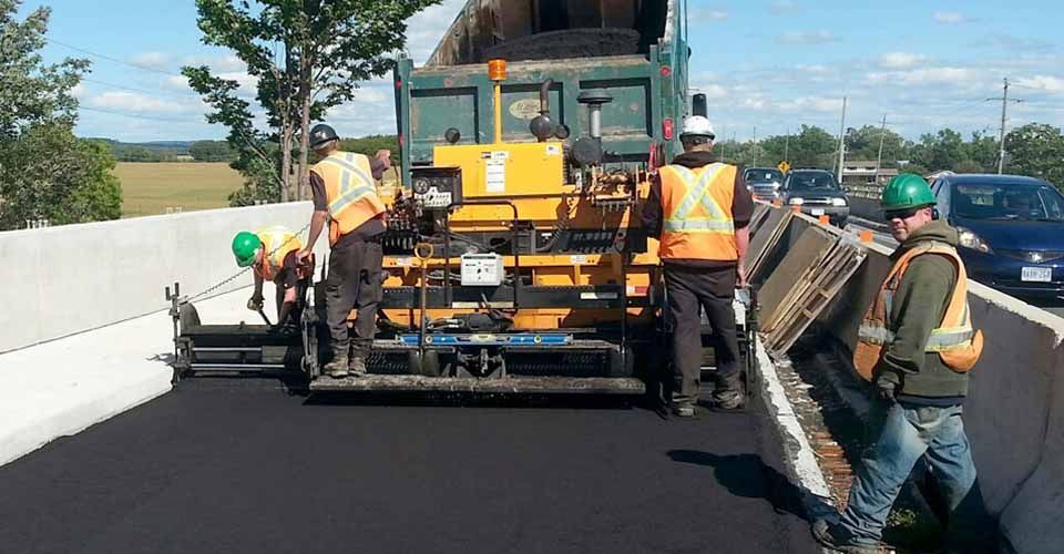 workers paving road with paving machine