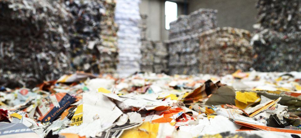 Rifiuti e carta ingombrano una discarica tra cumuli di scarti.