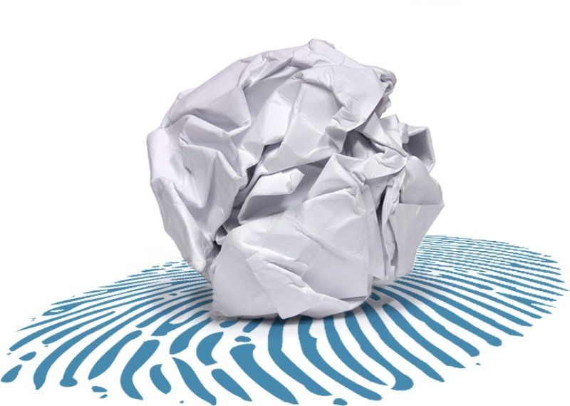 Pallina di carta bianca accartocciata su uno sfondo blu con motivo a impronte digitali.