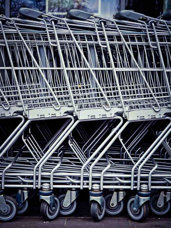 Carrelli della spesa in metallo impilati con ruote nere nel parcheggio di un negozio.