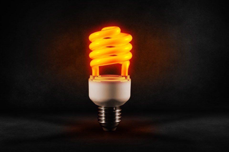 Lampadina fluorescente compatta a spirale arancione brillante su sfondo scuro