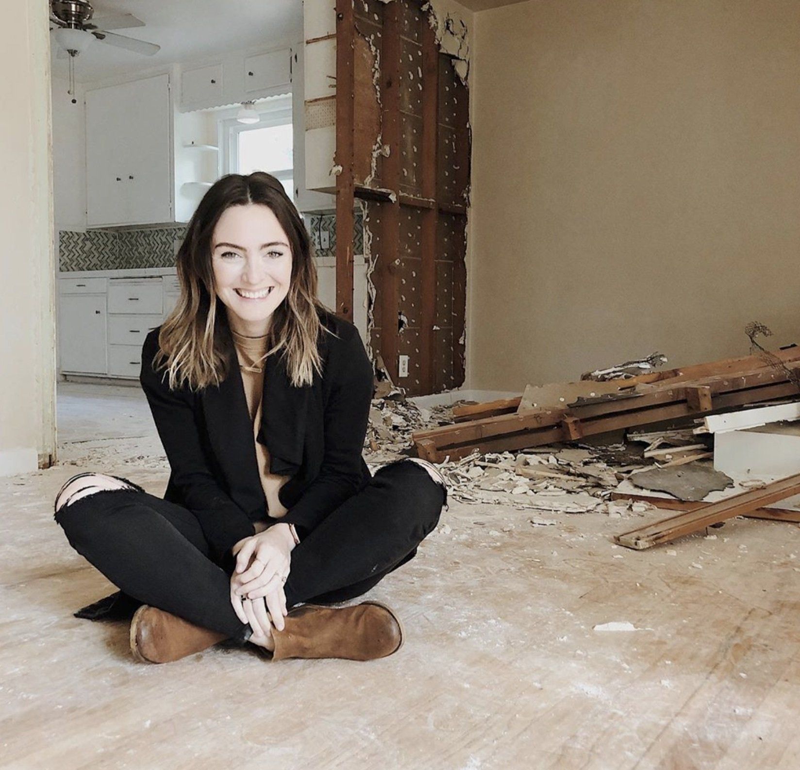 Debbie Mayes from The Mayes Team sits on the floor of the demolished living room of their tiny home in Northern California as they begin renovation on a budget.
