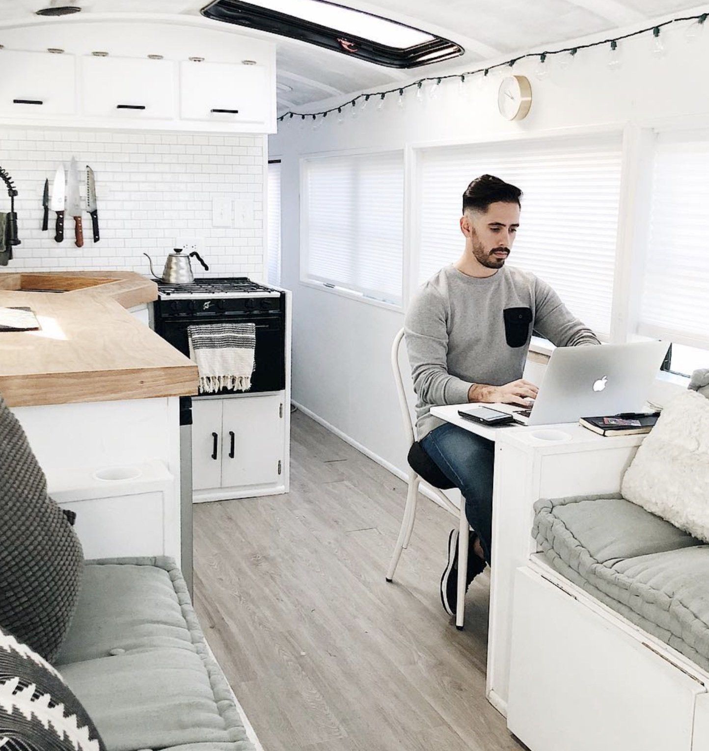 Gabriel Mayes sits at his laptop in the kitchen of the skoolie bus working on traffic hacking your competition.