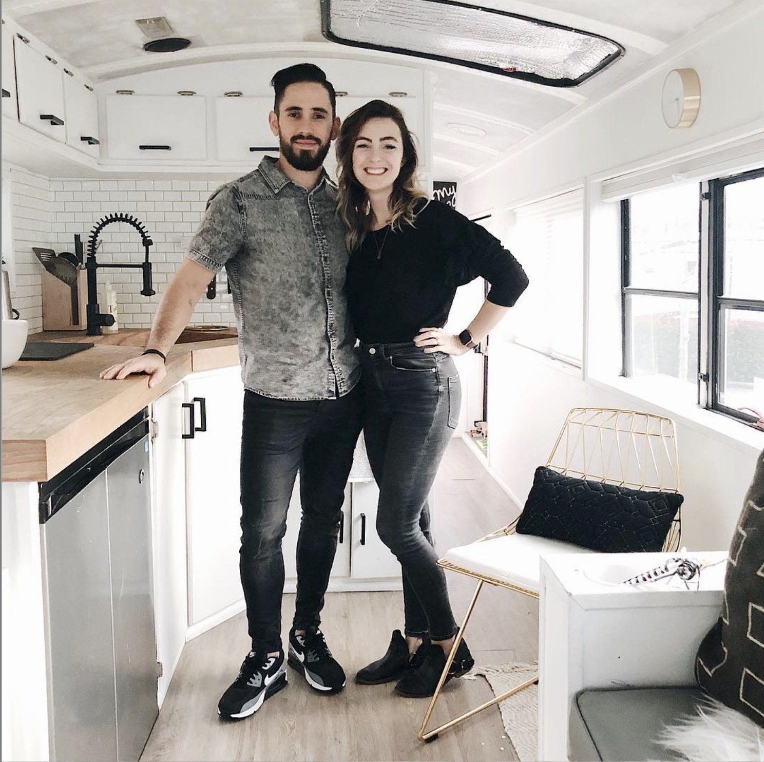Debbie & Gabriel Mayes stand in the kitchen of the skoolie smiling about what you need to build a 6-figure brand.