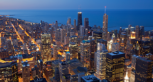 An aerial view of a city at night with a large body of water in the background.