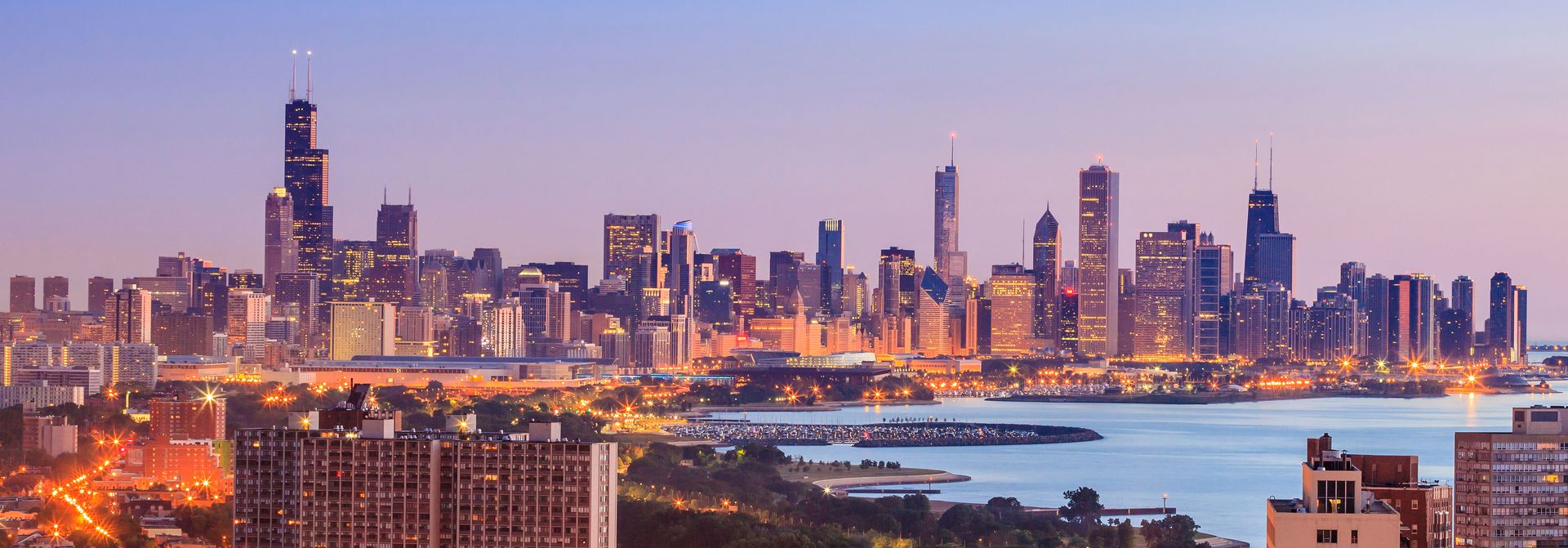 An aerial view of a city skyline at night with a body of water in the foreground.