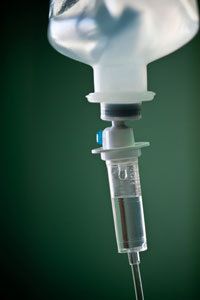 A close up of an intravenous drip with a bottle of liquid hanging from it.