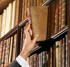 A person is picking up a book from a bookshelf