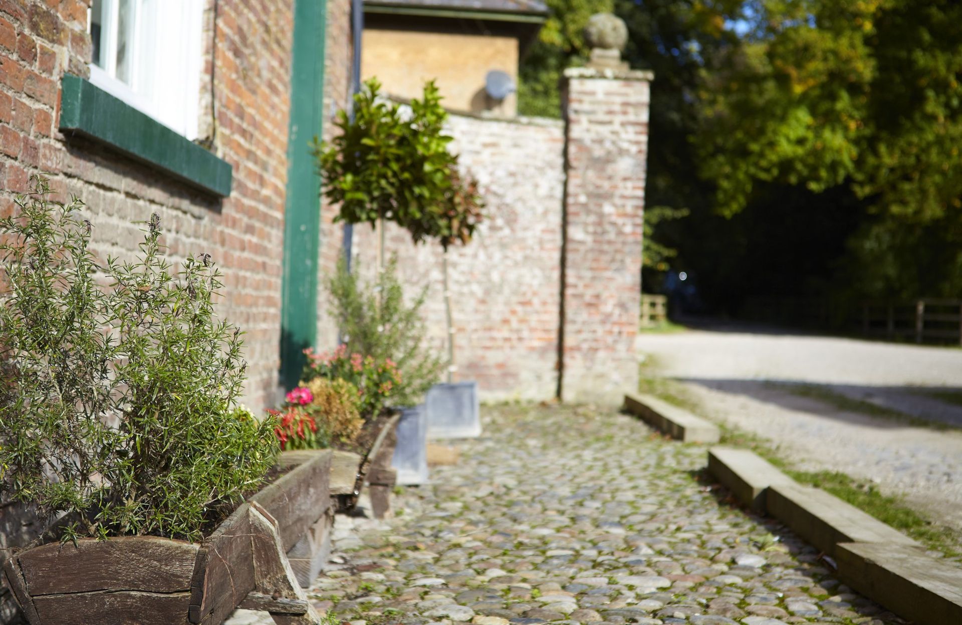 Brick building exterior with a cobblestone path and greenery.