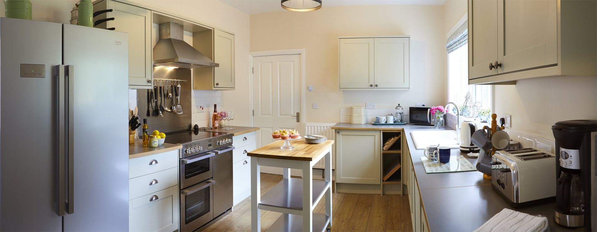 A kitchen with white cabinets, stainless steel appliances, and a wood-top island.