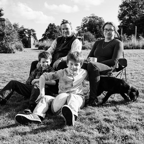 Family of four and dog sitting on grass outdoors.