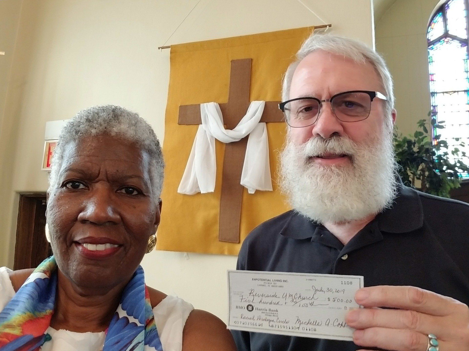 A man and a woman holding a check in front of a cross