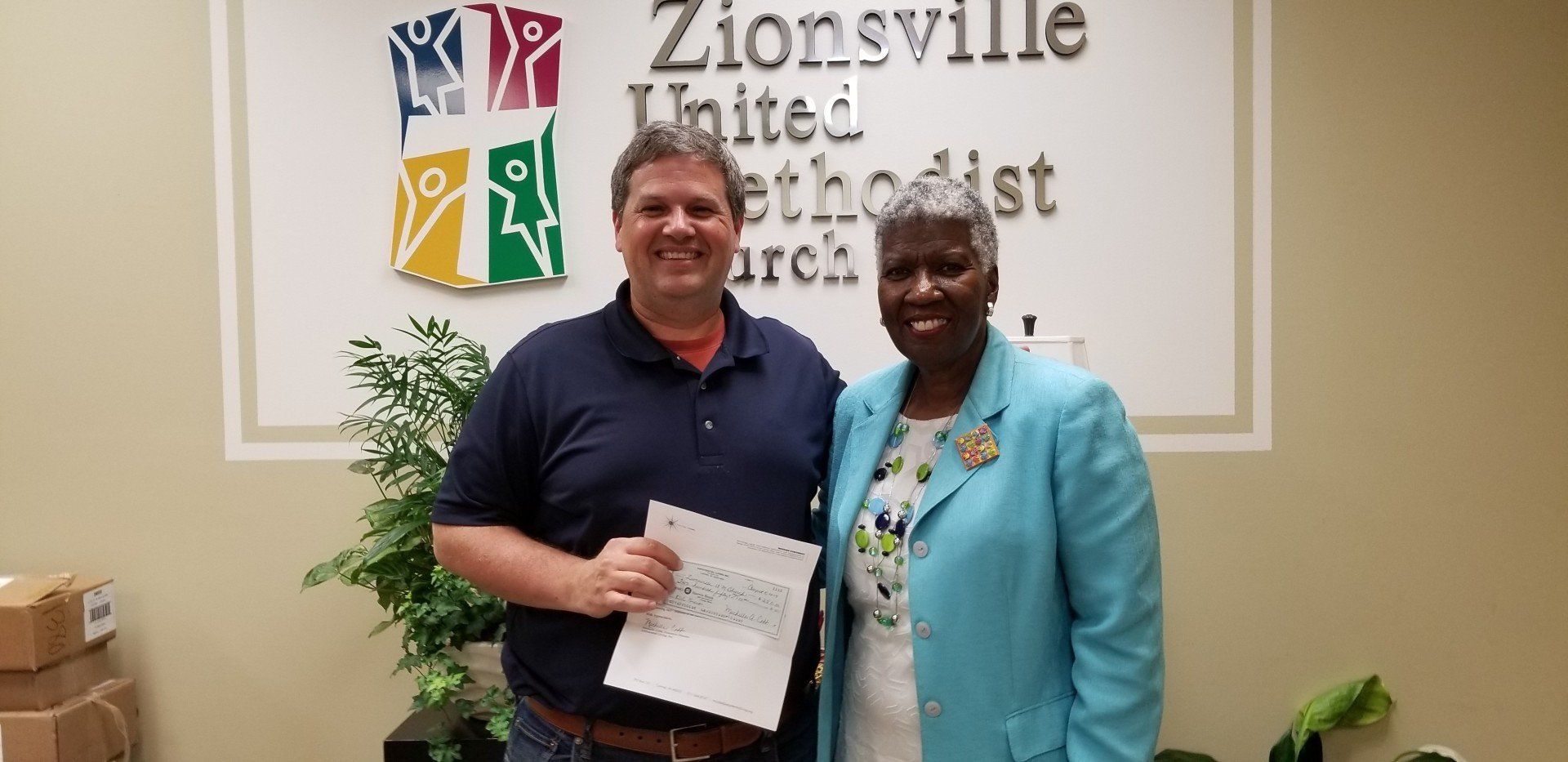 A man and a woman are standing in front of a sign that says zionsville united methodist church