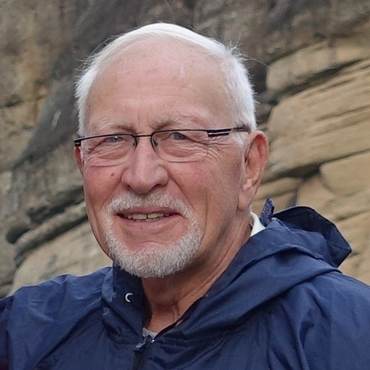 A man with glasses and a beard is wearing a blue jacket