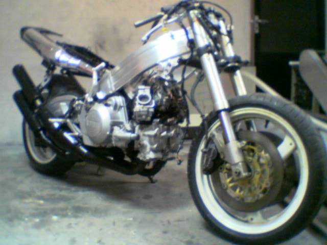 Custom silver-and-black motorcycle parked indoors, with whitewall tires and chrome details.
