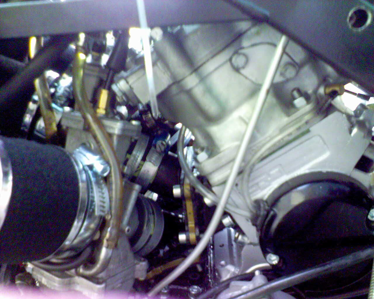 Close-up of mechanical components and hoses inside a machine, with metal fittings and brackets.
