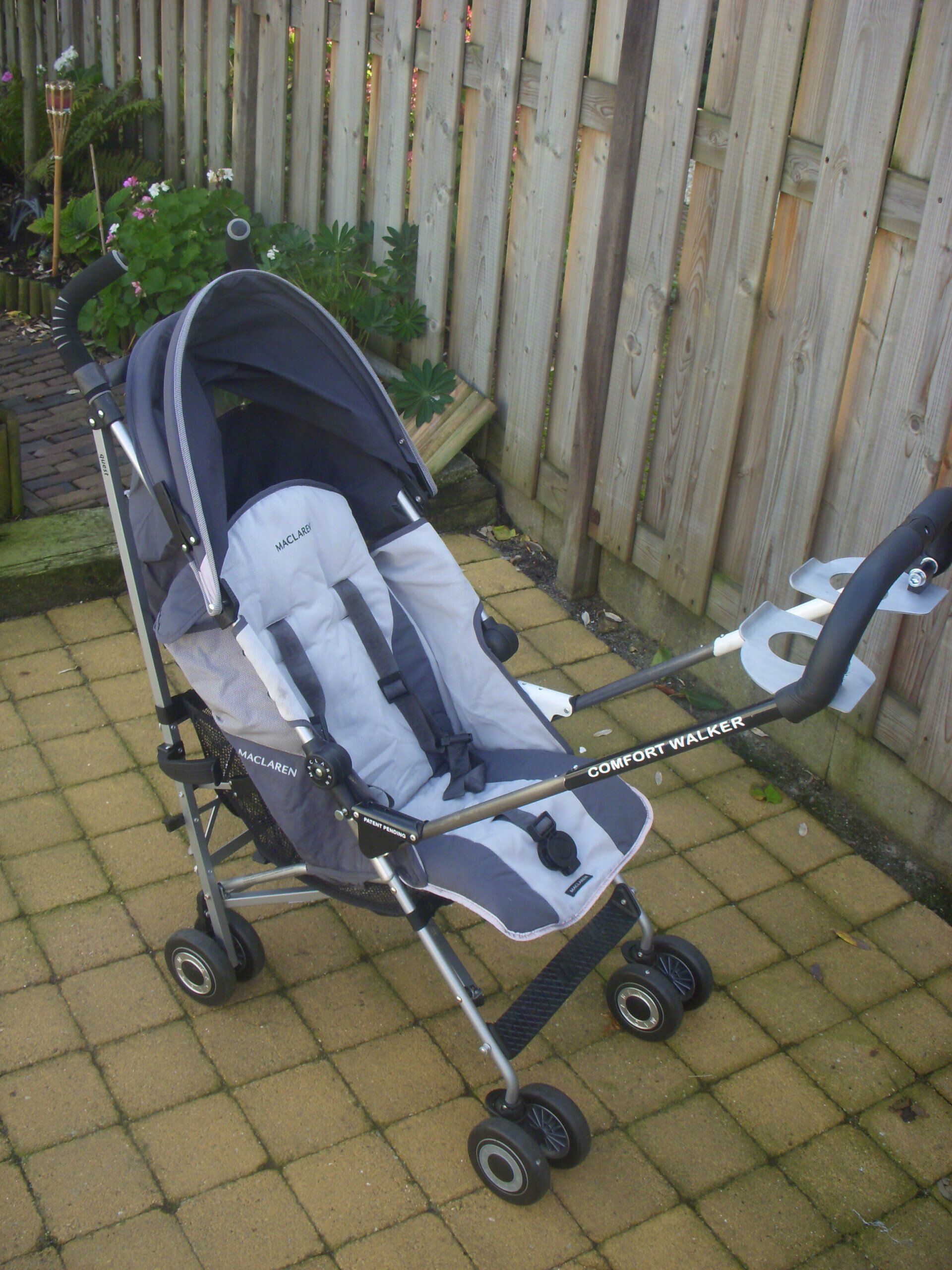 Empty stroller on patio beside a wooden fence, with a canopy and safety straps visible